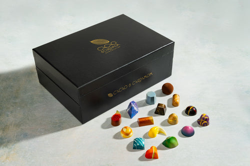 Black chocolate box with colorful chocolate bonbon on a light surface