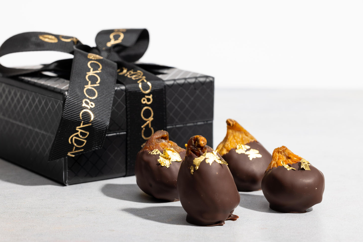 A box of chocolate-covered figs with a dark chocolate shell s on top