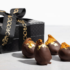 A box of chocolate-covered figs with a dark chocolate shell s on top