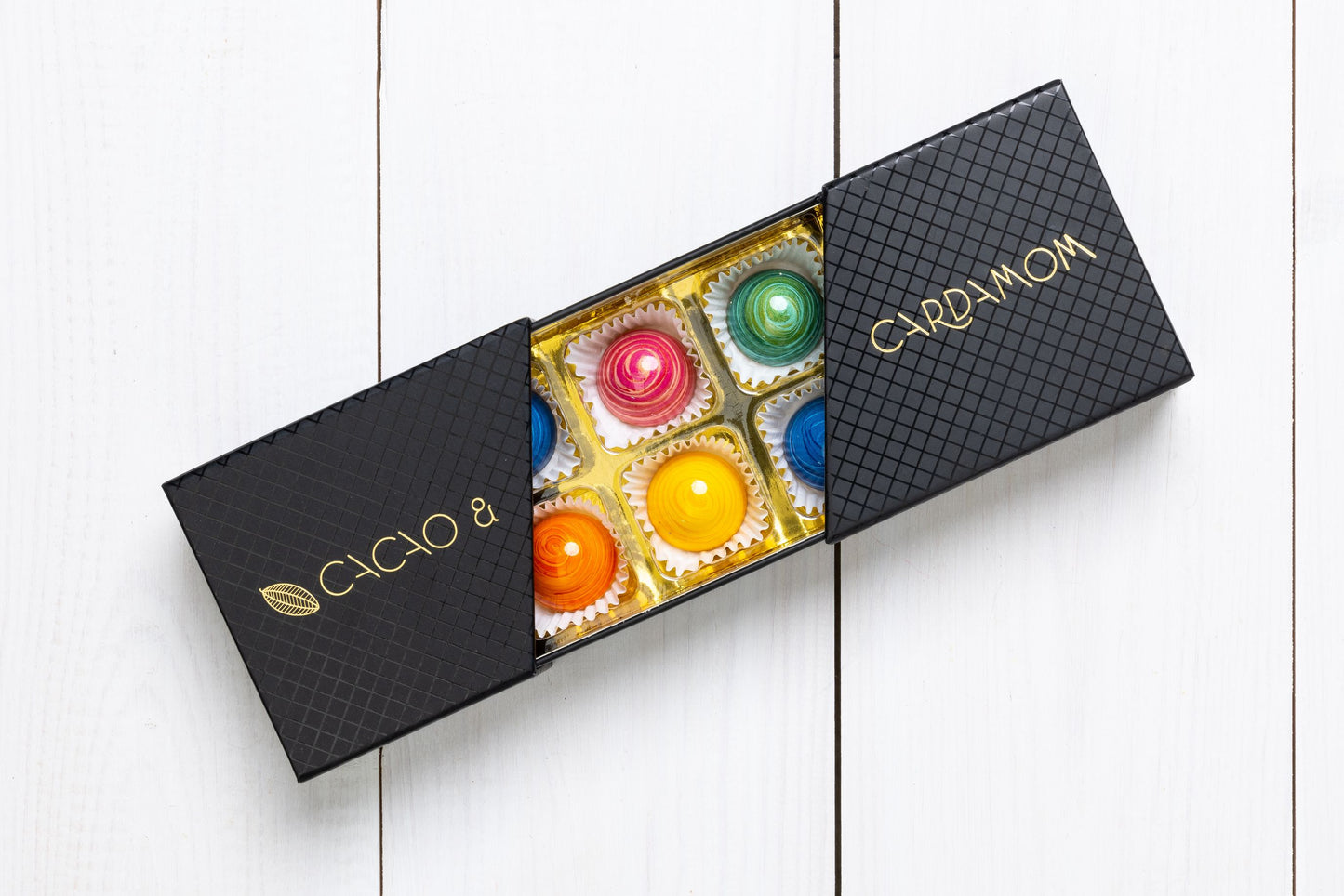 A box of assorted chocolates from the Summer Collection, with visible colorful candies and a label that reads 'COCO & CARDAMOM'.